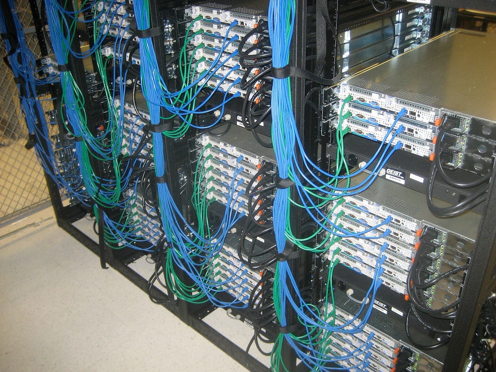 Rows of rack-mounted servers, each with blue and green network cables bundled along the side of the rack