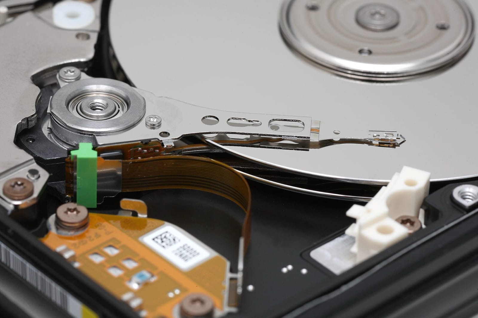 The inside of an opened hard disk: a polished platter with a metal arm reaching across it, the read/write head at its tip