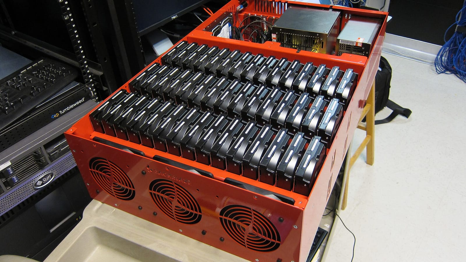 An open red storage server chassis packed with three rows of hard drives