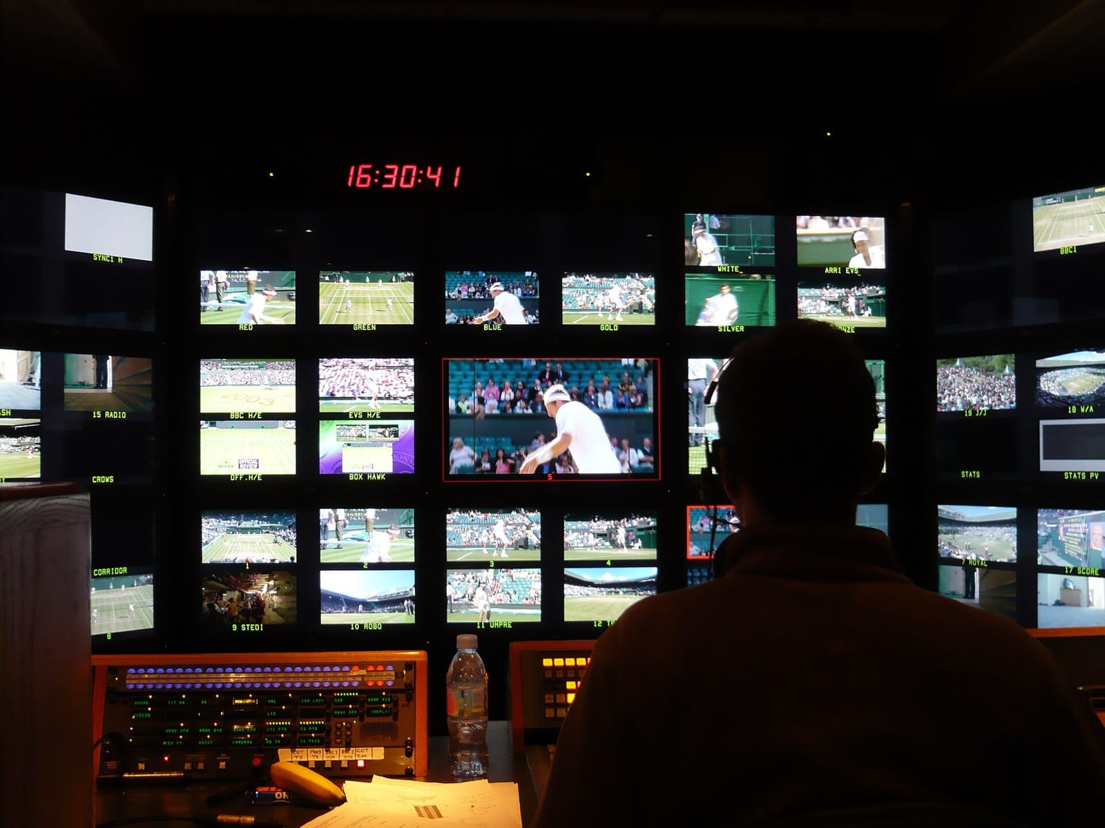 The inside of a broadcast production truck, with rows of monitors above a vision mixing desk