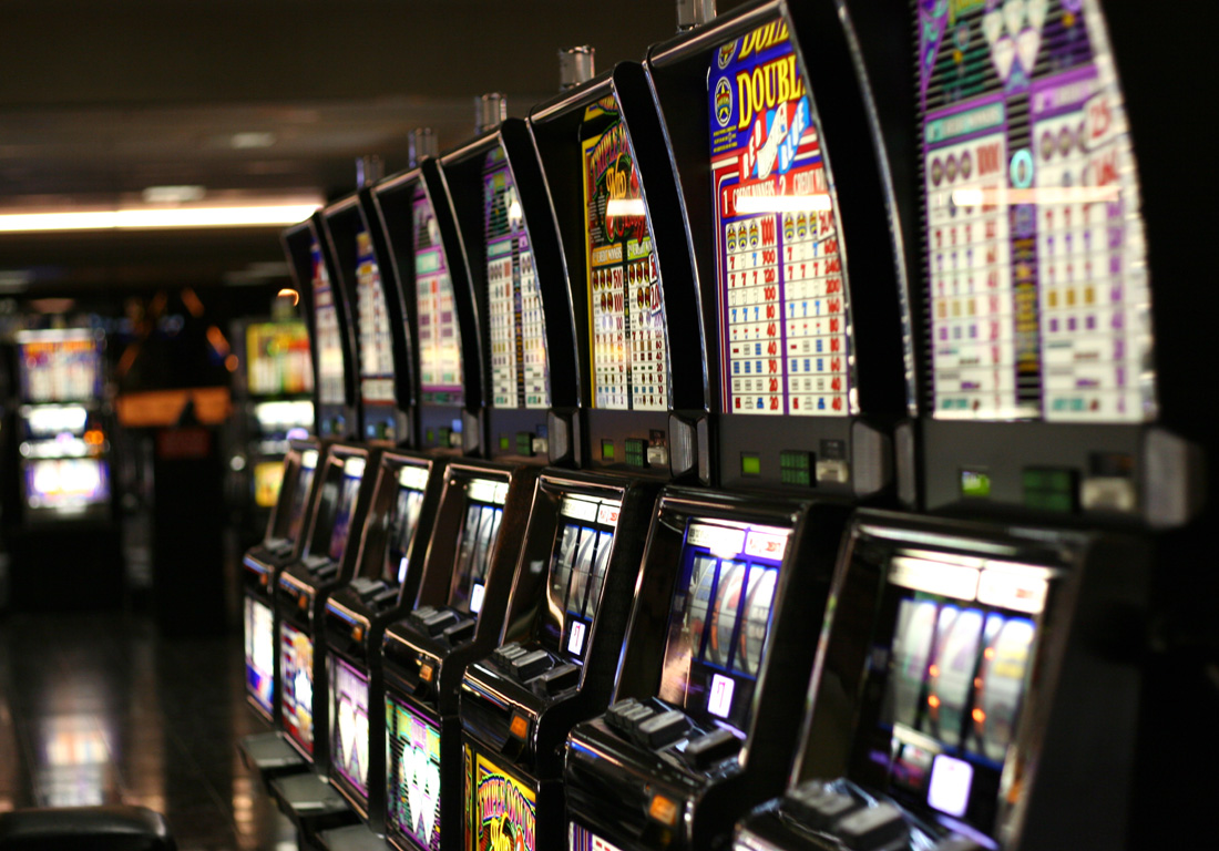 A long row of lit slot machines in a casino