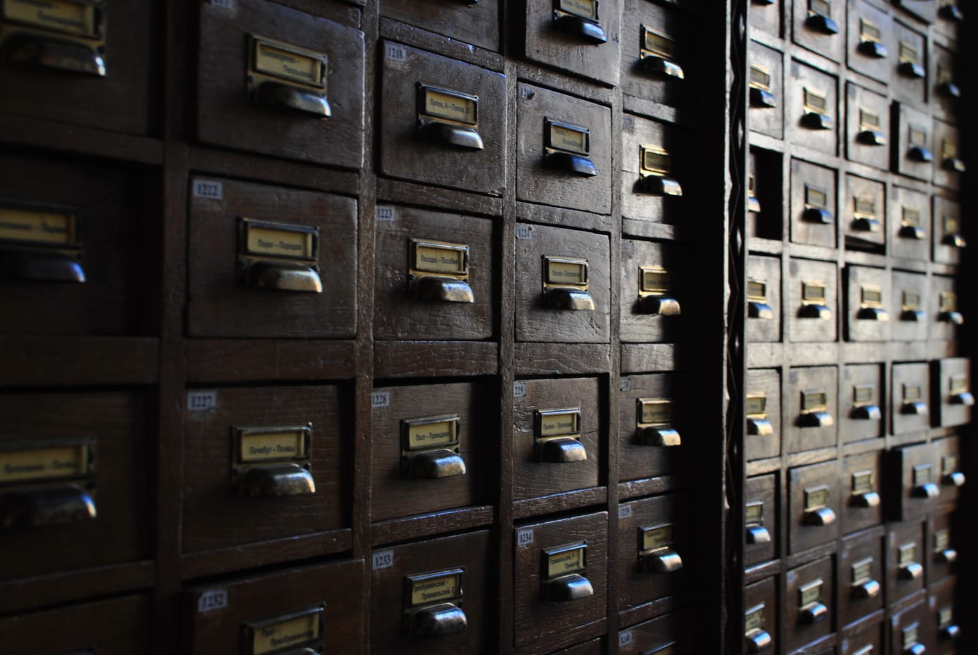 Rows of small wooden card-catalogue drawers, each with a brass label holder