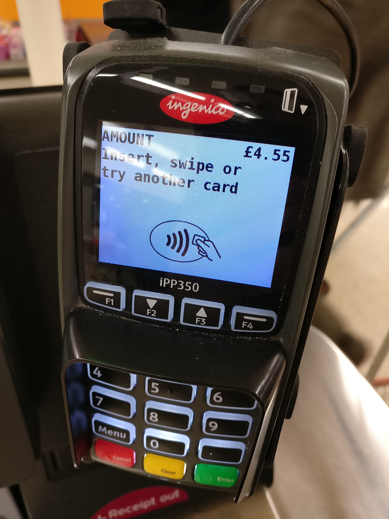 A card payment terminal at a shop checkout showing AMOUNT £4.55 and the words Insert, swipe or try another card