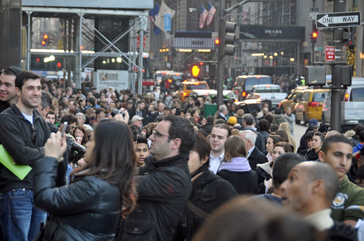 A dense crowd of shoppers filling a Manhattan street on Black Friday, with yellow taxis behind them