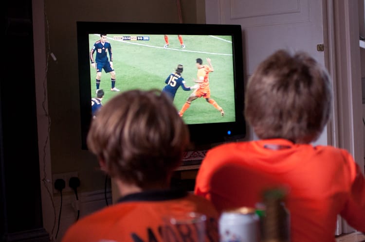 Two children in orange Netherlands shirts watching the 2010 World Cup final on a television