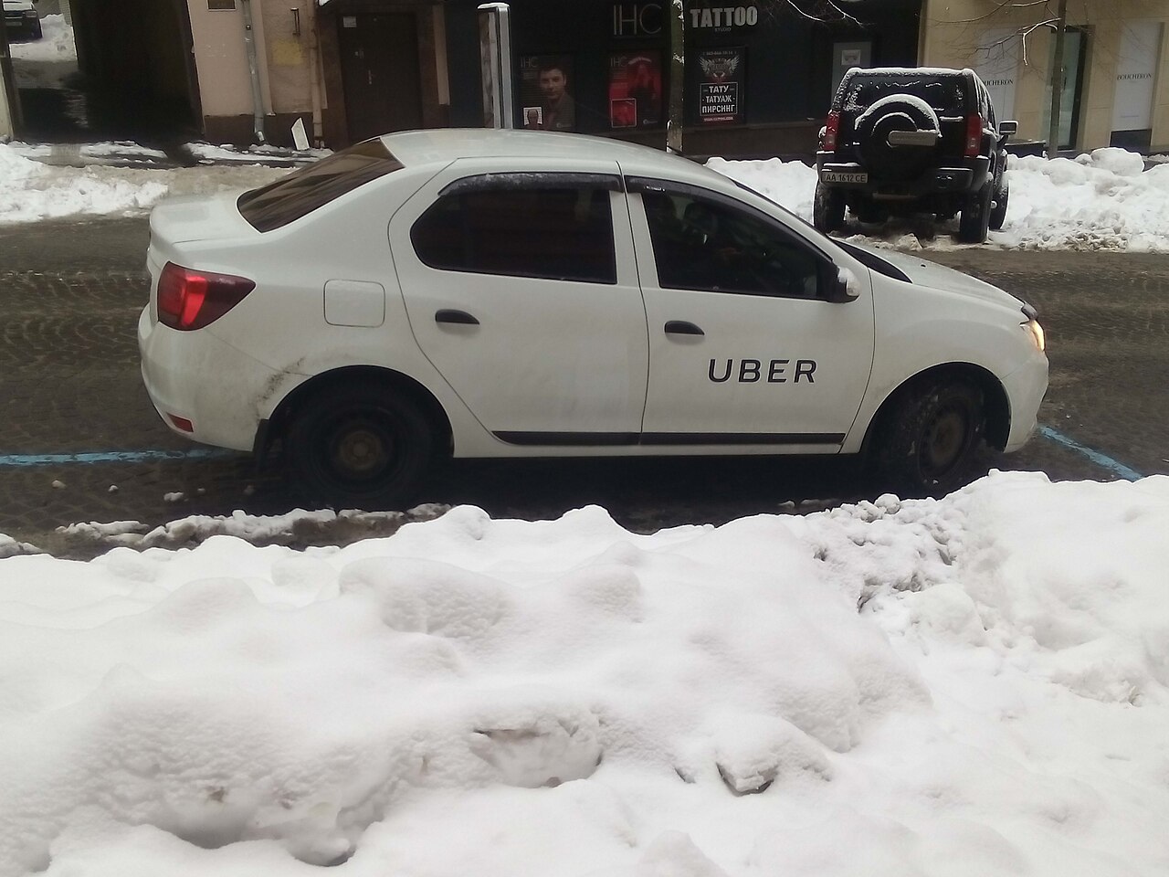 An Uber-branded car parked on a snowy city street