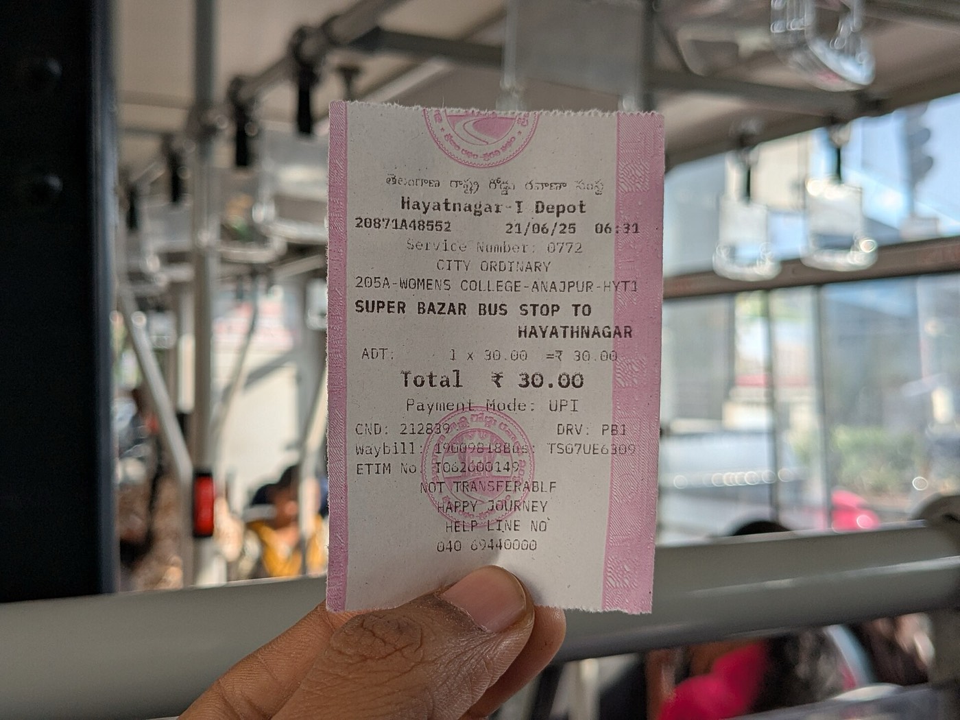 A hand holding a printed city bus ticket from Hyderabad showing a total of 30 rupees and Payment Mode: UPI