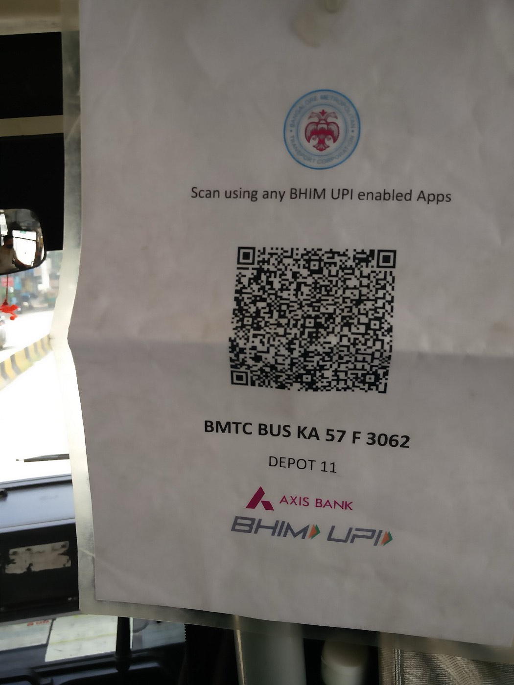 A paper notice inside a Bengaluru city bus with a QR code and the words Scan using any BHIM UPI enabled Apps, with Axis Bank and BHIM UPI logos
