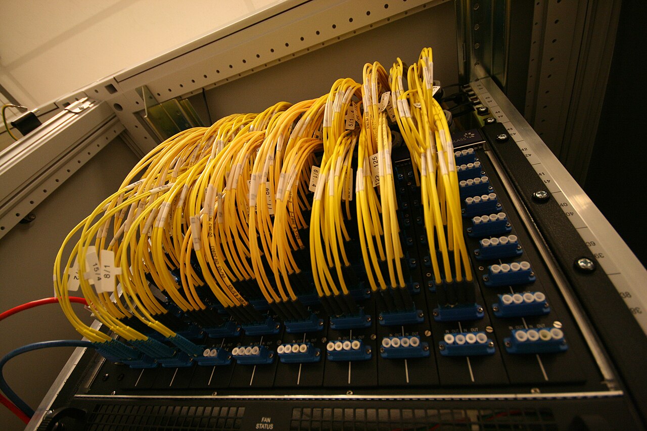 Rows of yellow fibre cables plugged into blue connector modules in a rack at an internet exchange